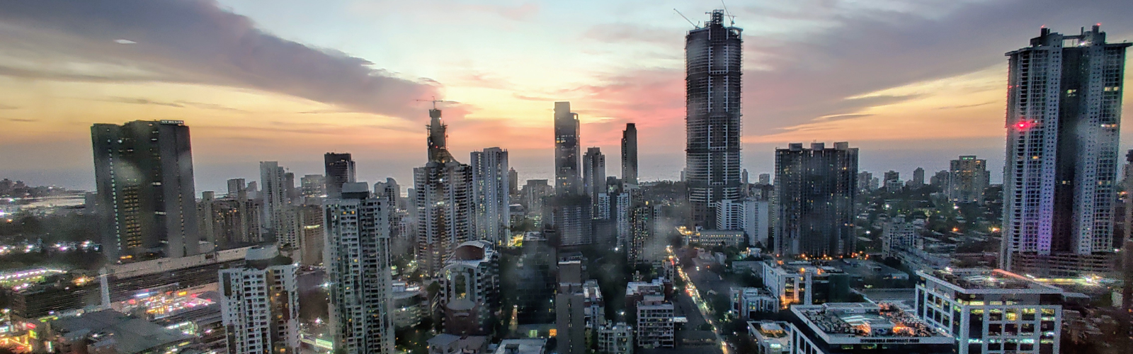 The Mumbai skyline with many tall skyscrapers with a sunset in the background. 